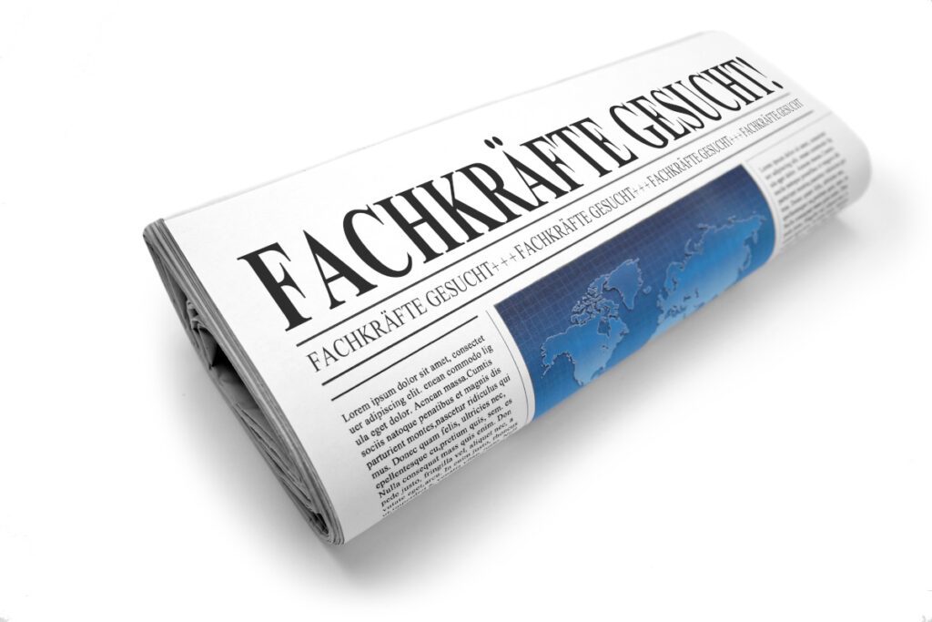 Zusammengerollte Tageszeitung mit der Schlagzeile Fachkräfte gesucht